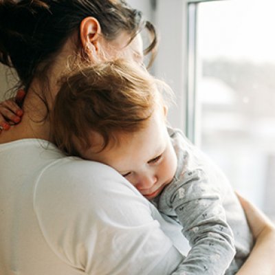 A mother holding a young toddler in her arms